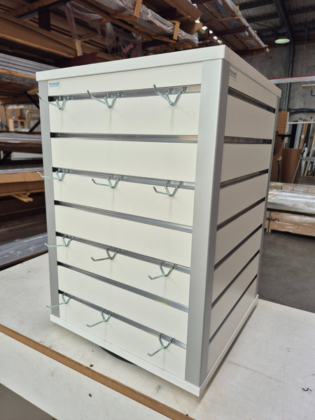 white rotating counter top retail display stand with prongs in a factory setting