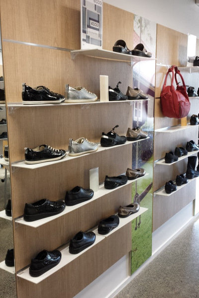 Melamine shelving in white 6mm on wooden slatwall displaying shoes in a retail store