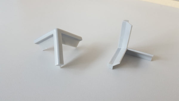 close up shot of 2 MC3 integral colour 3 way corners on a white desk