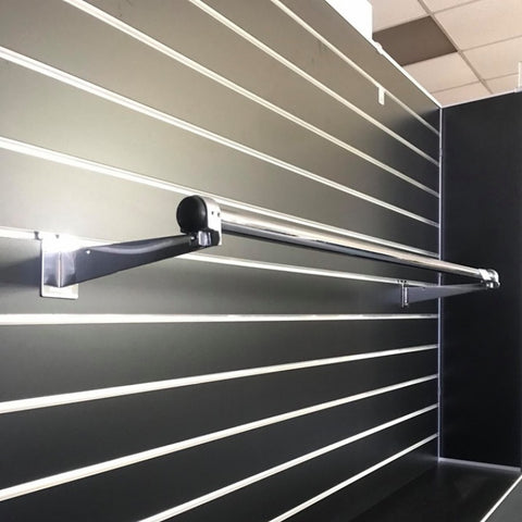 A chrome garment rail tube mounted on a wall bracket, part of a slatwall display system.