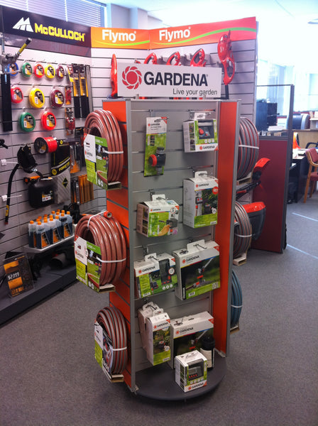 Plankwall grey rotating Slatwall Retail display stand with two red sode panels displaying garden products in retail shop