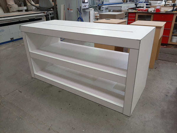 Photo of a Plankwall electronics retail display table in white with shelving underneath shown in factory