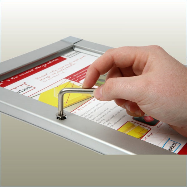 A person's hand using a security key to release a Plankwall lockable snap poster frame.