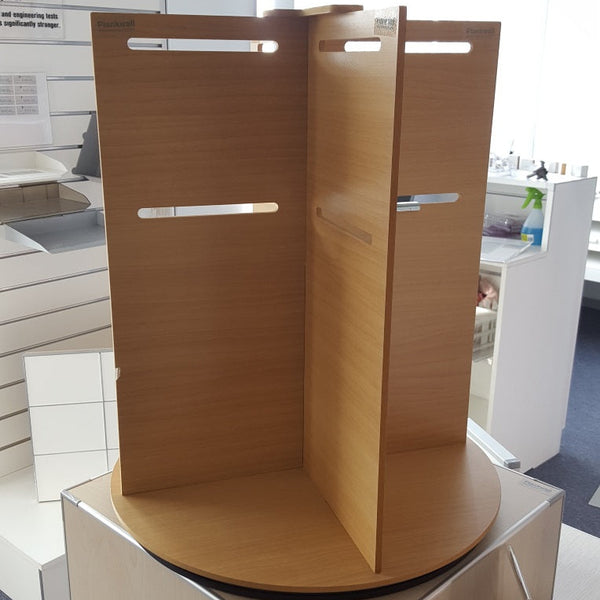 A Plankwall wooden mini rotating display stand with a turntable base, featuring slots for hooking in display prongs and a room on top for a sign holder in a showroom