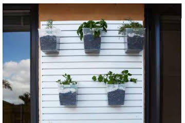 Plankwall white All Ali 50mm pitch aluminium slatwall used as a hanging garden outside with mounted pot plants
