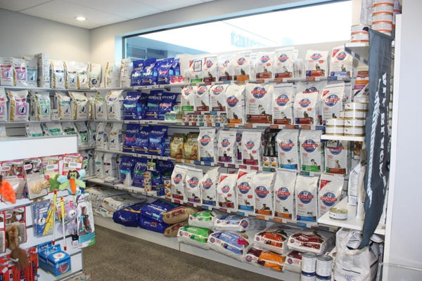 white shelves mounted on white slatwall panels with pet food at Tuaranga vets