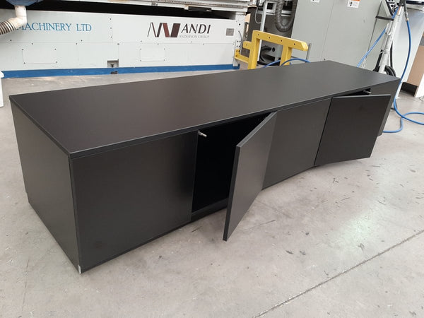 Black cabinets in a workshop setting with machinery in the background