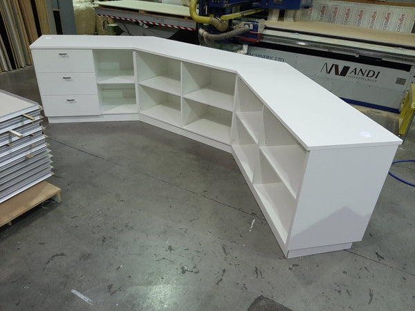 White L-shaped reception desk or retail counter in a workshop setting