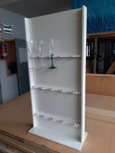 White glass rack with wine glasses on a wooden surface in a warehouse setting