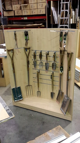 Set of gardening tools on a wooden display board in an indoor setting.