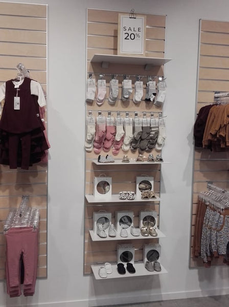 Retail wall display of baby clothes shown on Plankwall slatwall panel in light oak with 6mm white melamine shelves